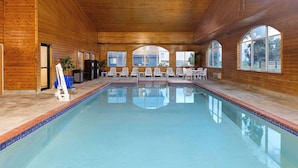 A large indoor pool with wooden walls and multiple windows. - AmericInn by Wyndham Grinnell (Grinnell)