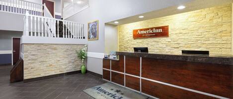 A reception area with a stone wall, a wooden reception desk, and a staircase.