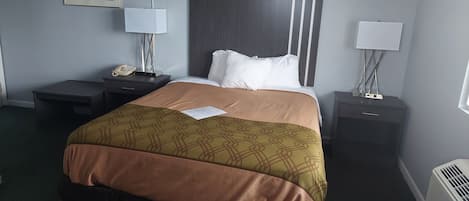 Una habitación de hotel con una cama, dos mesitas de noche, una lámpara, un teléfono y un calefactor.