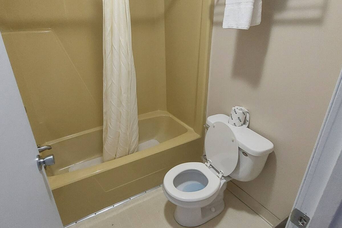A bathroom with a bathtub, toilet, and shower curtain.