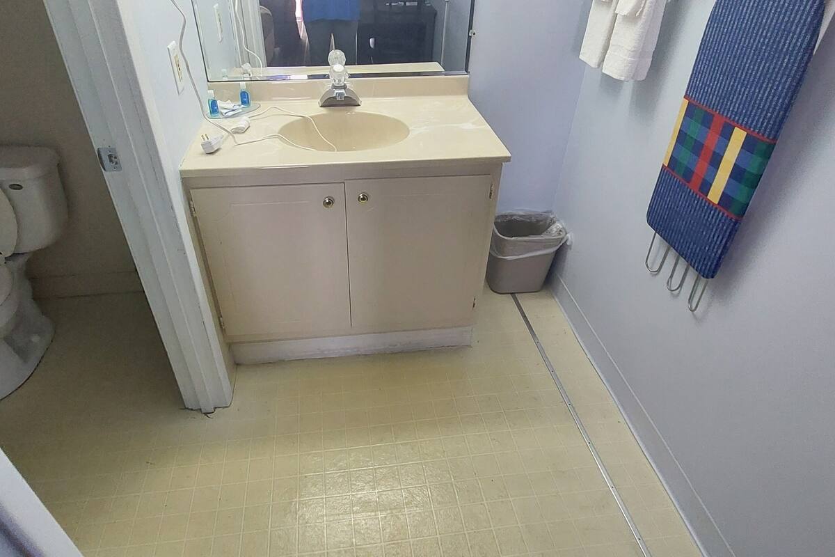 A bathroom with a toilet, sink, and mirror.