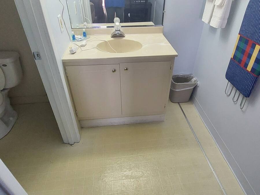 A bathroom with a toilet, sink, and mirror.