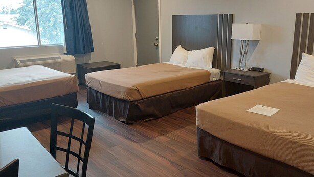 Habitación de hotel con tres camas, un escritorio y una silla.
