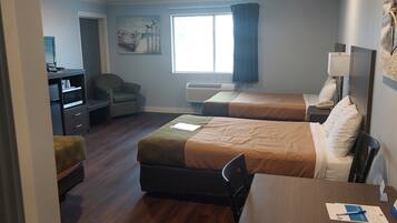 A hotel room with two beds, a desk, a chair, a TV, a chair, a window with curtains, and a painting on the wall.