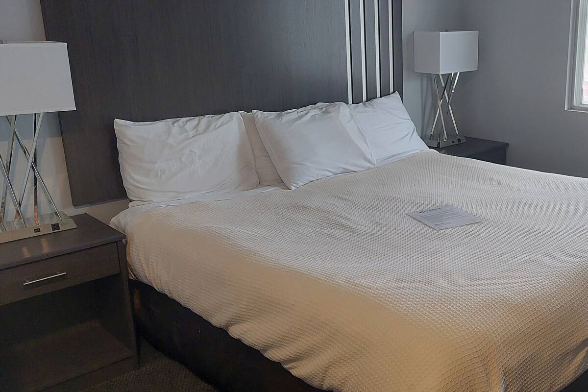 A neatly made bed with white linens in a hotel room.