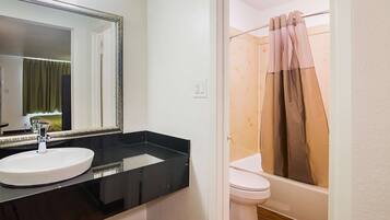 A bathroom with a white sink, a mirror, a toilet, and a shower curtain.