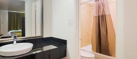 A bathroom with a white sink, a mirror, a toilet, and a shower curtain.
