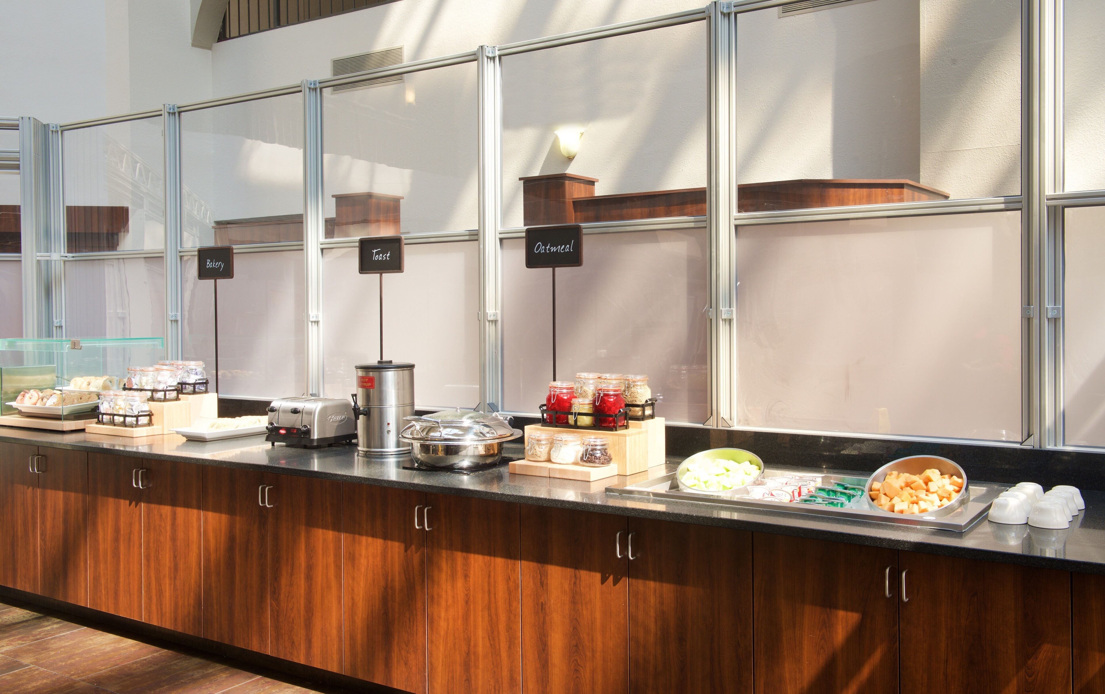 A buffet counter with labeled sections for toast, oatmeal, and bakery items.