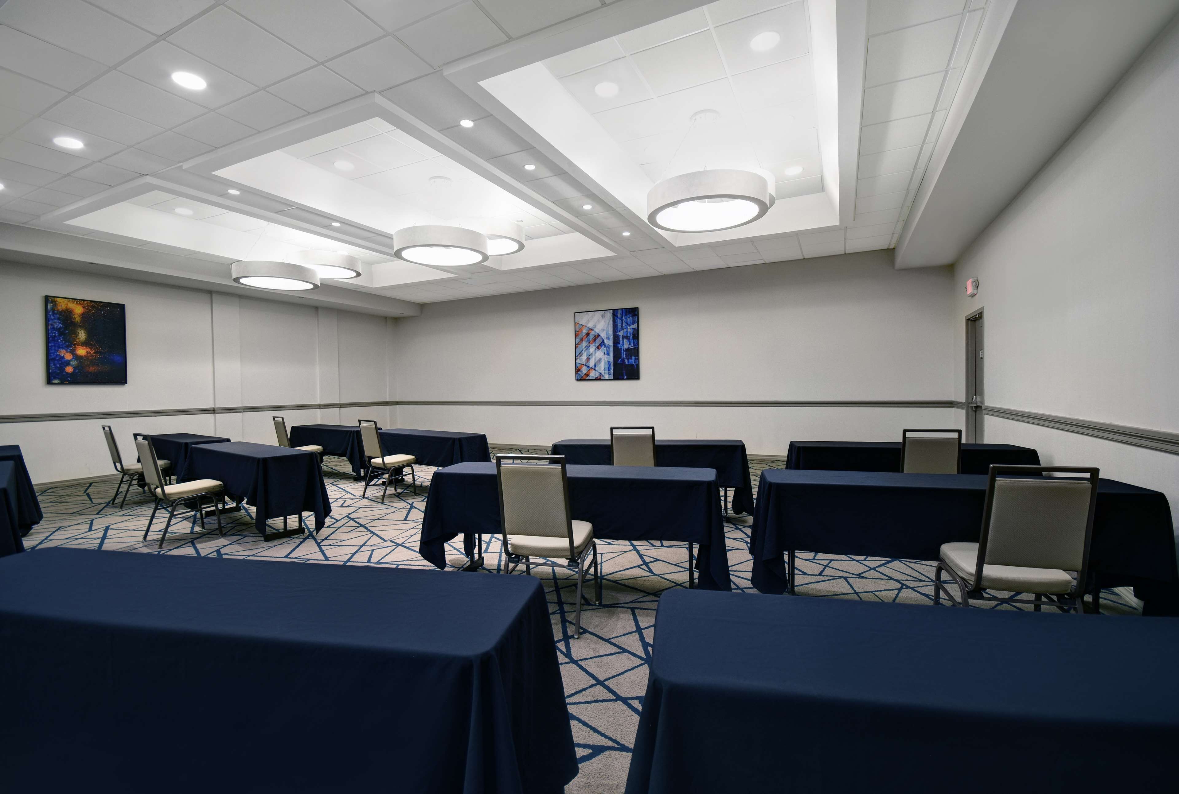 A conference room with tables and chairs, recessed lighting, and artwork on the walls.