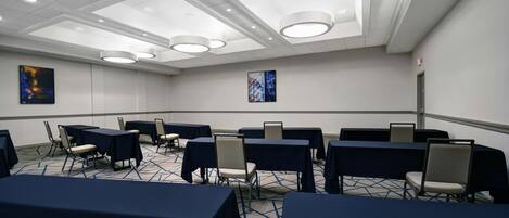 A conference room with tables and chairs, recessed lighting, and artwork on the walls.