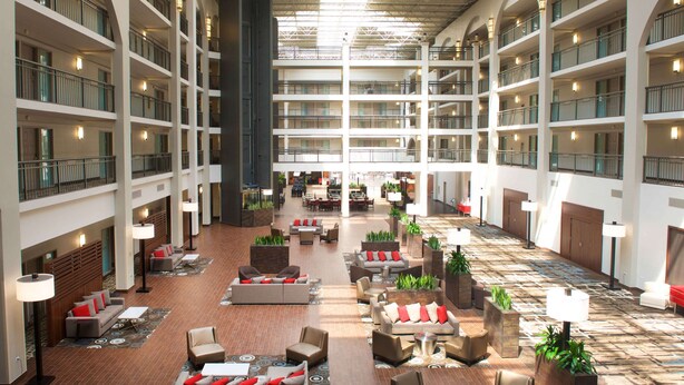 A spacious hotel atrium with multiple floors, a central open area with seating, and balconies on each floor. - Embassy Suites by Hilton Detroit Livonia Novi (Livonia)
