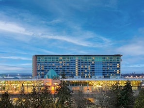Un hotel moderno con fachada de vidrio, un techo verde distintivo y vistas del entorno.