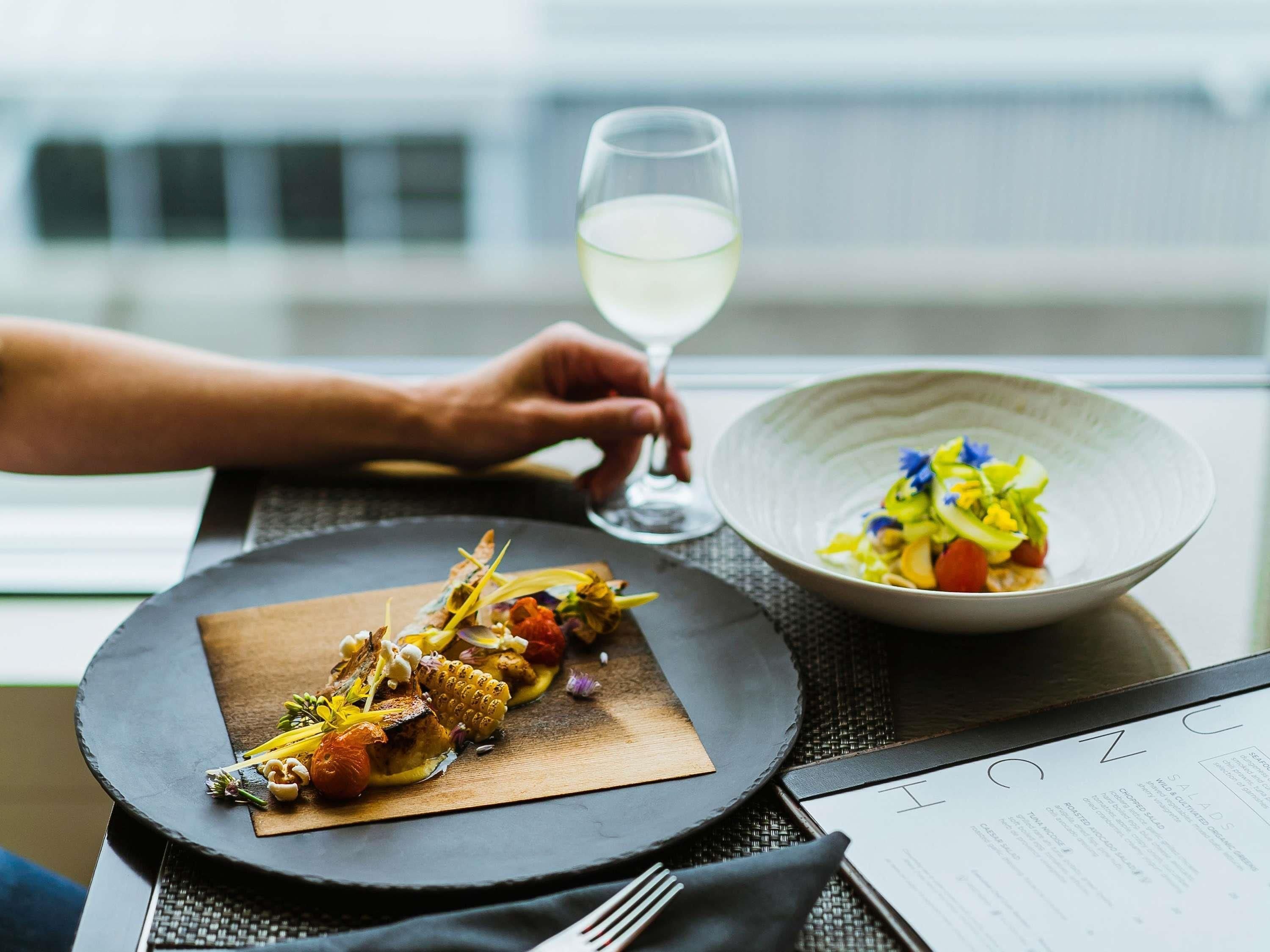 A dining table with a plate of food, a bowl of salad, and a menu.