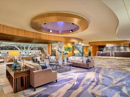 A spacious lobby with a central seating area, a staircase, and a reception desk.