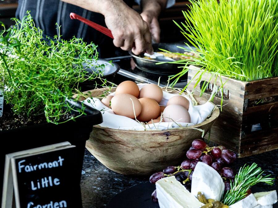 Un chef preparando comida con huevos, verduras y queso sobre una encimera de cocina.