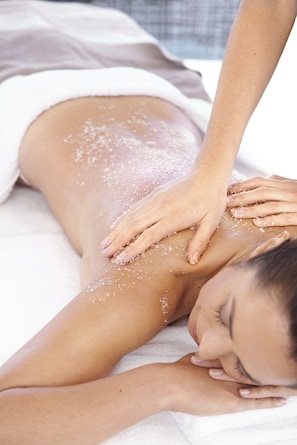 Iemand ontvangt een massage waarbij zout op de rug wordt aangebracht.