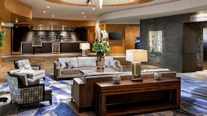 A modern lobby with a central seating area, a reception desk, and a stone fireplace.