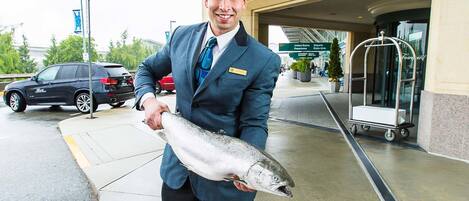 A man holding a fish in front of The Fairmont Vancouver Airport.