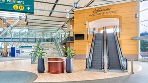 Un terminal d’aéroport moderne avec une enseigne indiquant l’hôtel Fairmont et l’hôtel Fairmont Vancouver Airport.