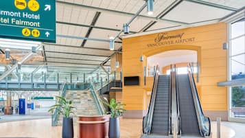 En moderne lufthavnsterminal med skilt for Fairmont Hotel og Fairmont Vancouver Airport.