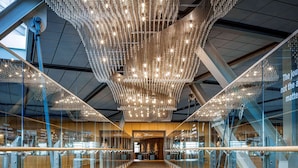 A modern interior with a patterned floor, glass railings, and a unique chandelier.