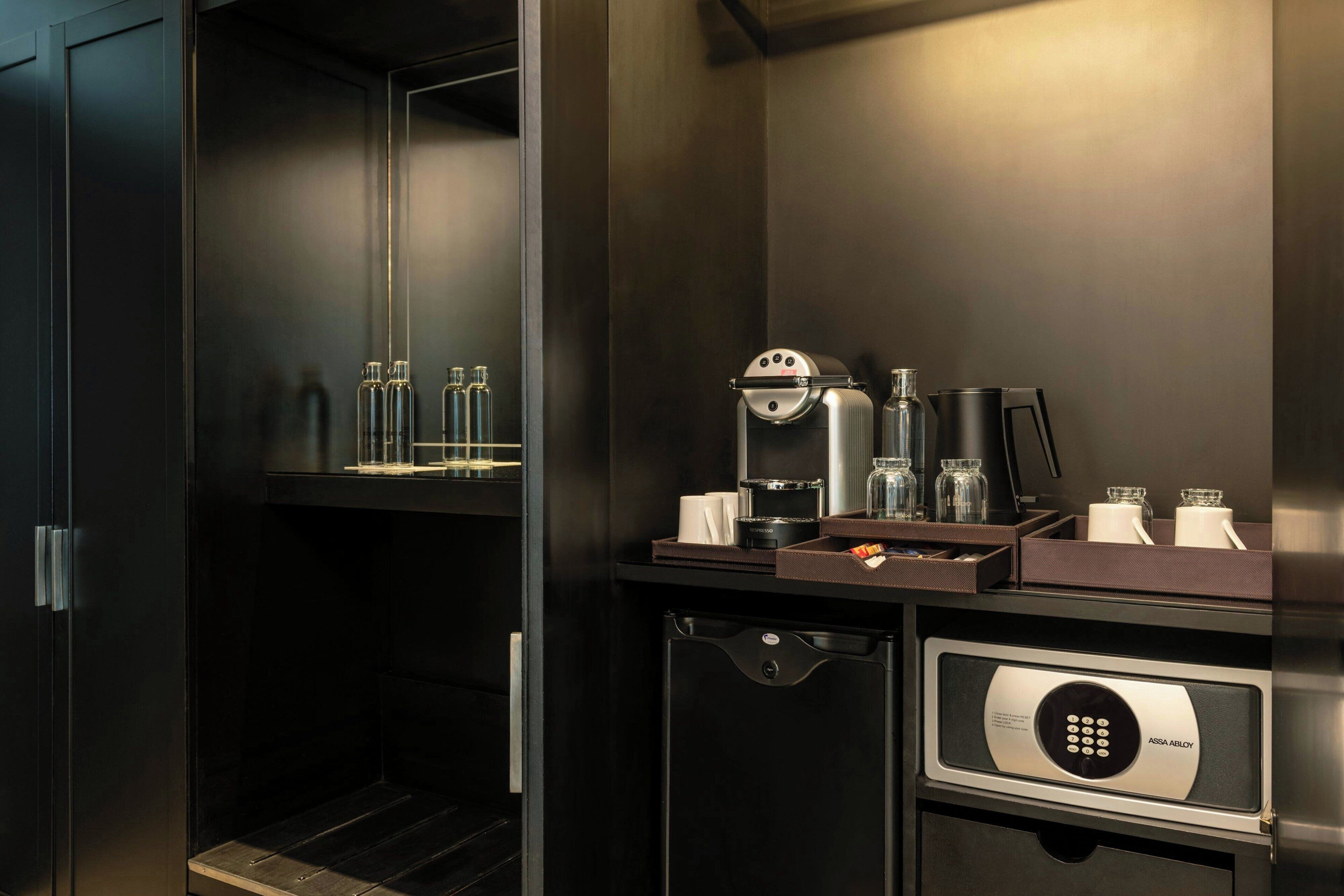 A compact kitchenette with a coffee machine, a microwave, and a small refrigerator.