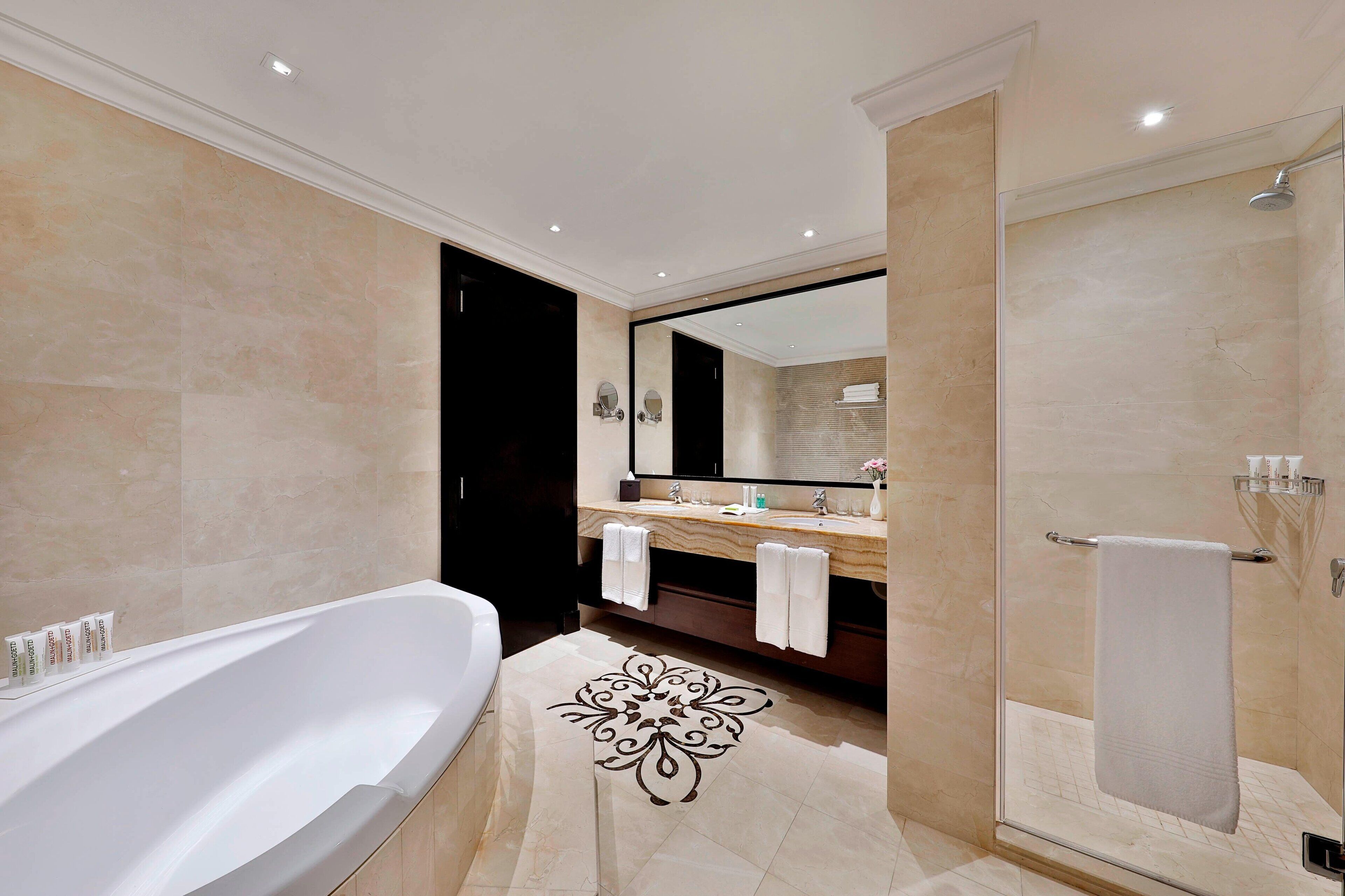 A modern bathroom with a freestanding bathtub, a glass-enclosed shower, and a vanity with a mirror and towel rack.