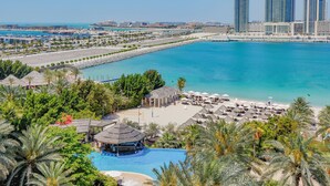 Un resort con piscina, zona de playa y vistas a un horizonte urbano.