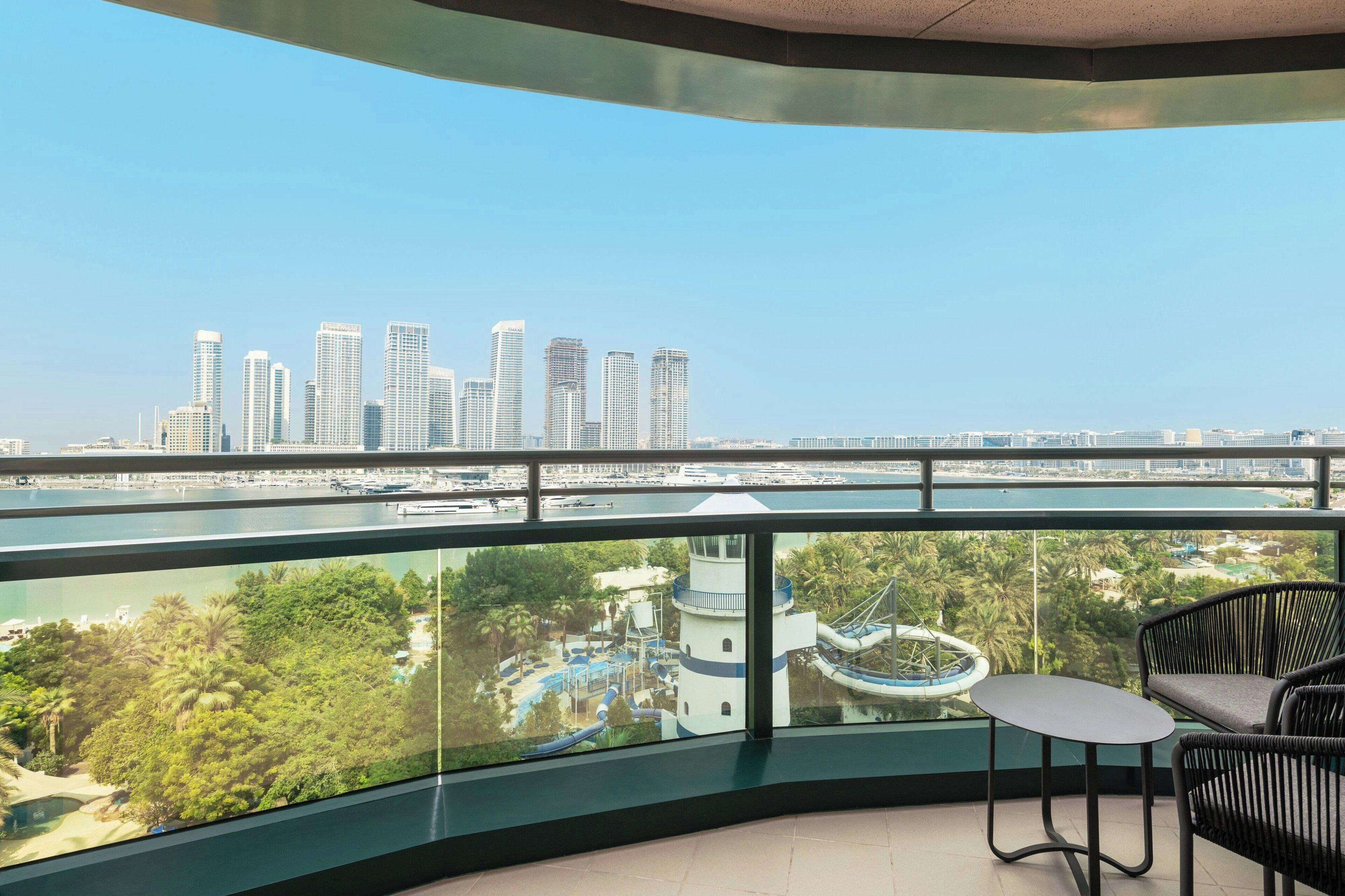 A balcony with a view of a city skyline, a water body, and a theme park.