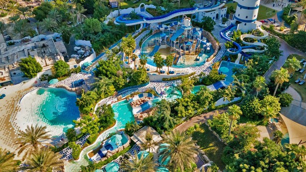 Vista aérea de un resort con múltiples piscinas, un parque acuático y una estructura de faro.
