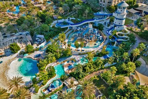 An aerial view of a resort with multiple swimming pools, a water park, and a lighthouse structure. - Le Méridien Mina Seyahi Beach Resort & Waterpark (Dubai)