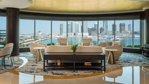 A modern living room with a large window offering a city view, a sofa set, and a coffee table.