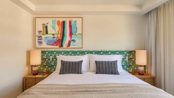 A hotel room with a bed, two pillows, a headboard with a geometric pattern, a painting on the wall, and two bedside lamps.
