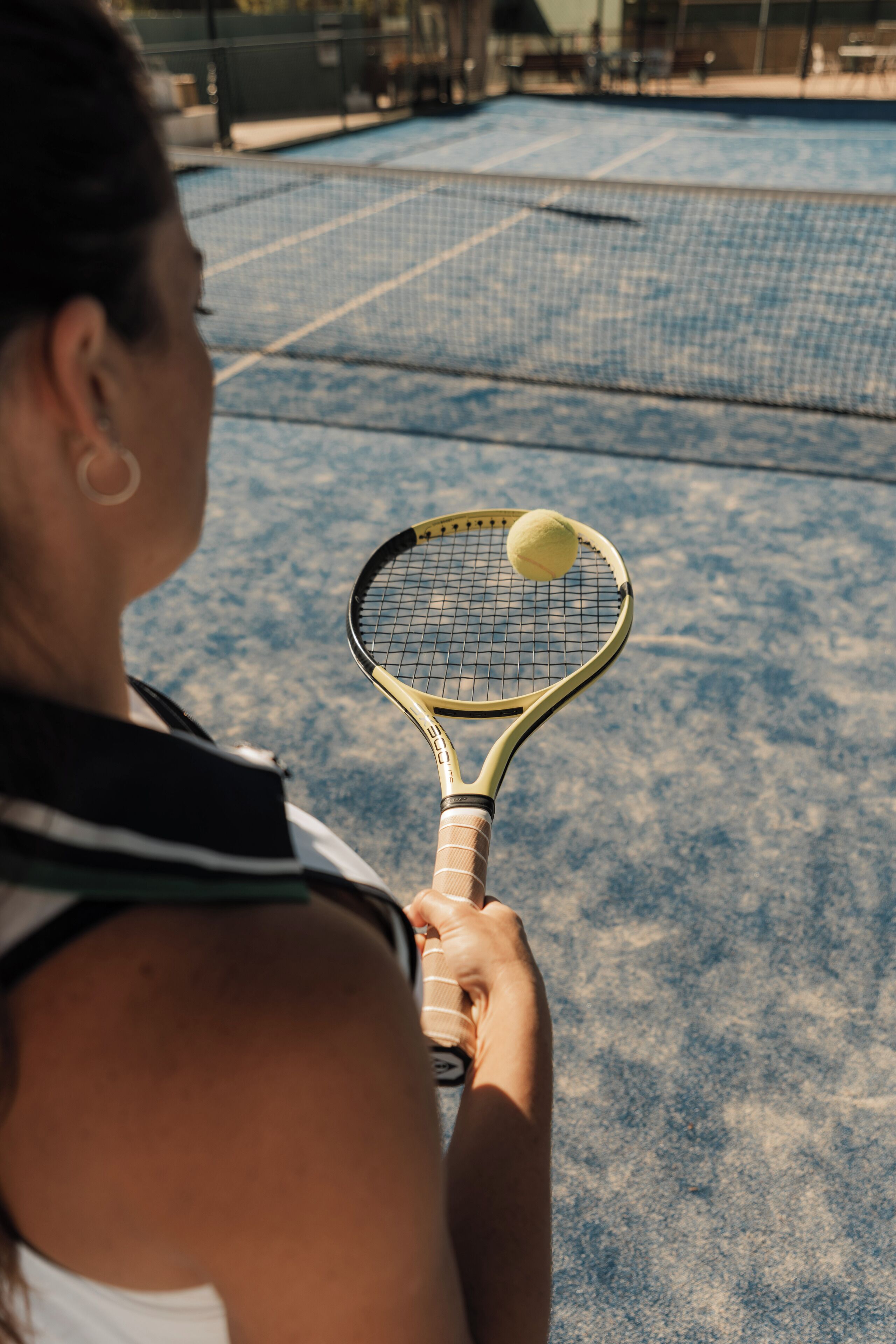 A tennis court with a player holding a racket and a tennis ball.