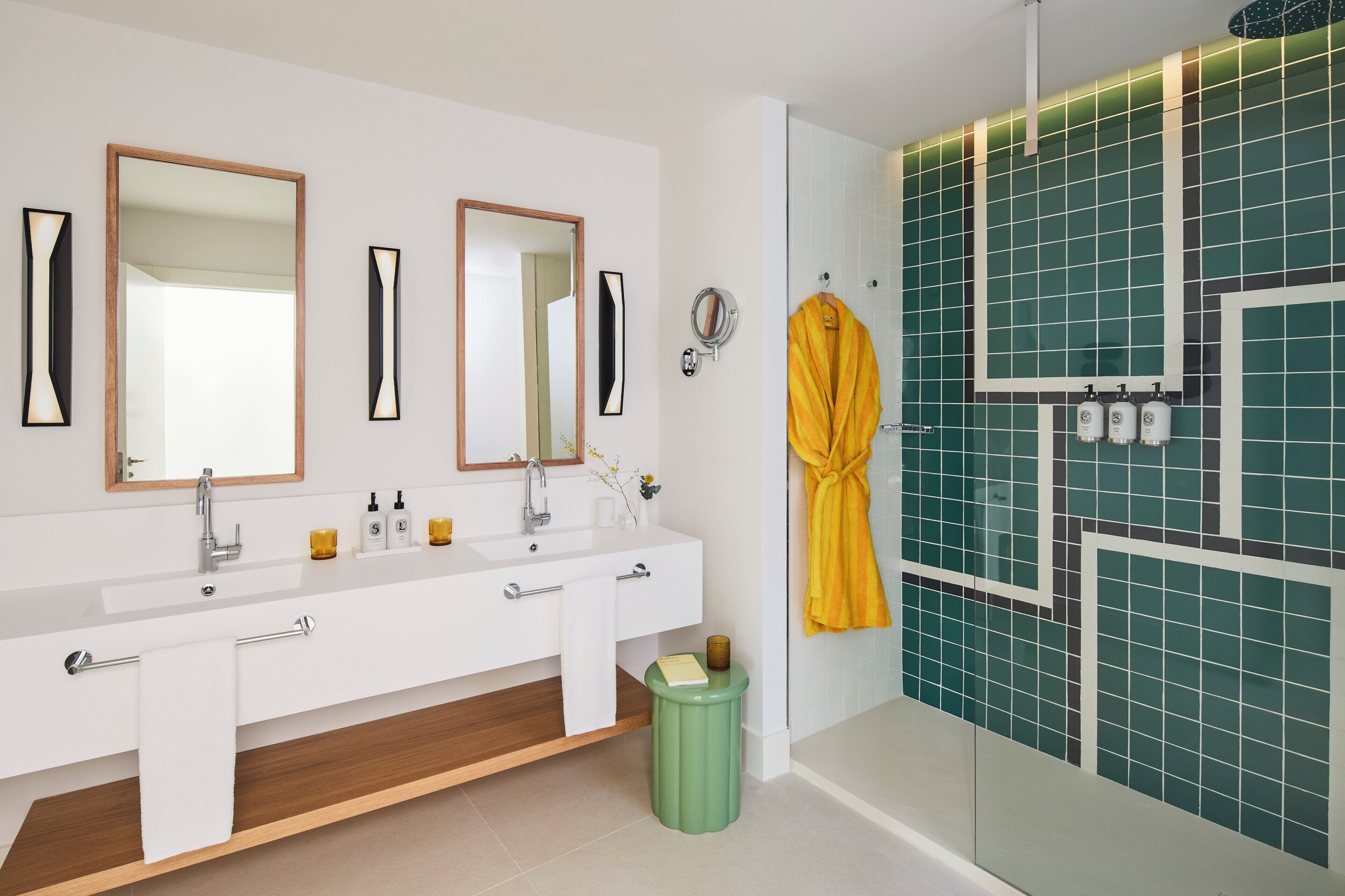 Une salle de bain moderne avec deux lavabos, des miroirs et un espace douche aux carreaux verts.