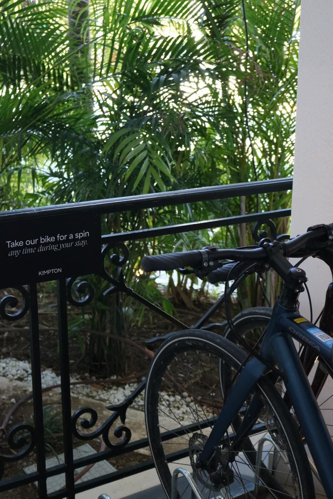 En cykel står parkerad bredvid ett metallräcke, och på en skylt står det: ”Använd vår cykel när du vill under din vistelse.”