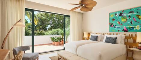 Ein geräumiges Schlafzimmer mit einem großen Bett, einer Sitzbank, einem Sessel und einem Deckenventilator.