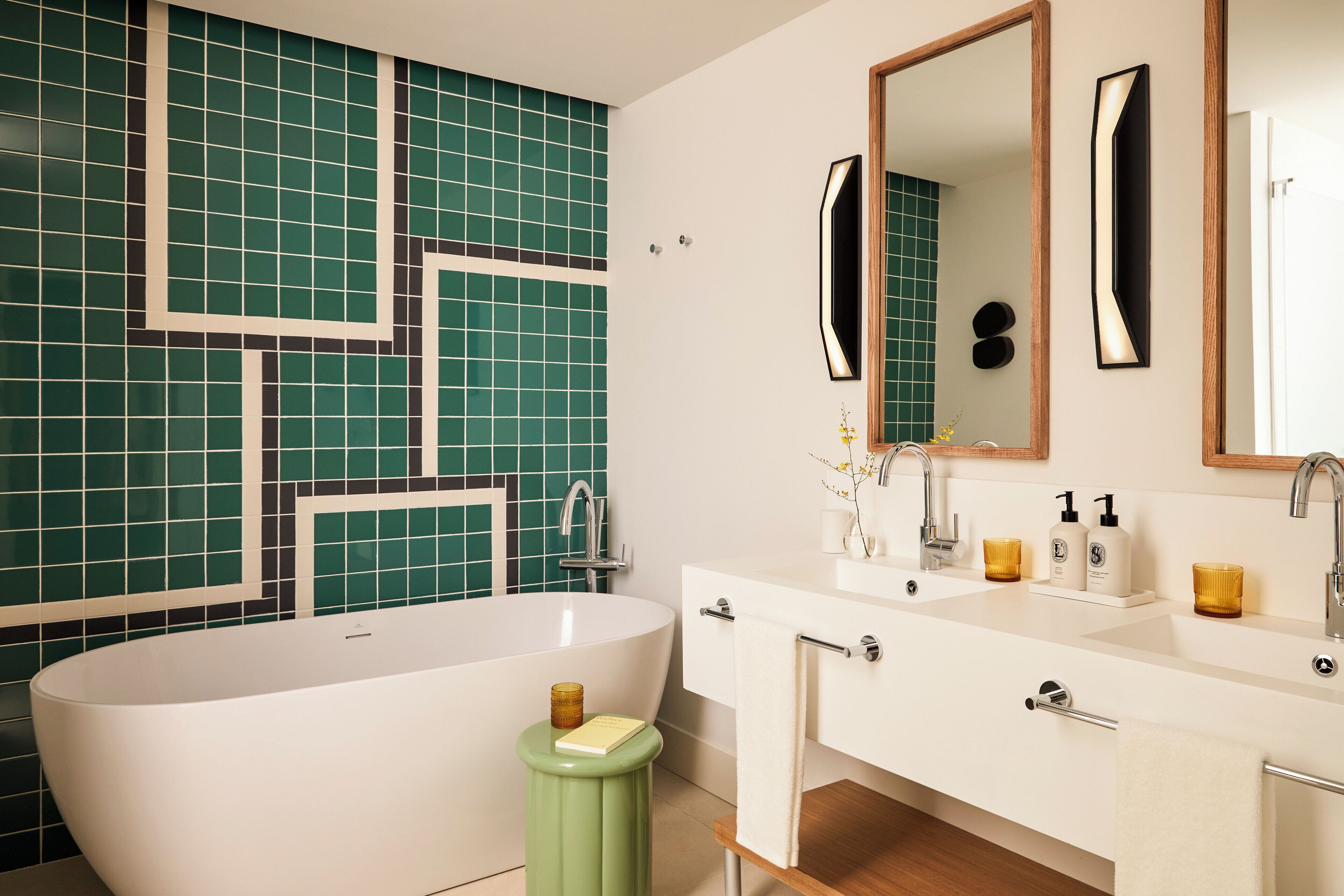 A modern bathroom with a freestanding bathtub, a vanity with a mirror, and a tiled wall.