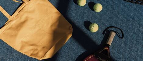 A tennis racket, a tennis ball, and a brown tote bag on a blue surface.