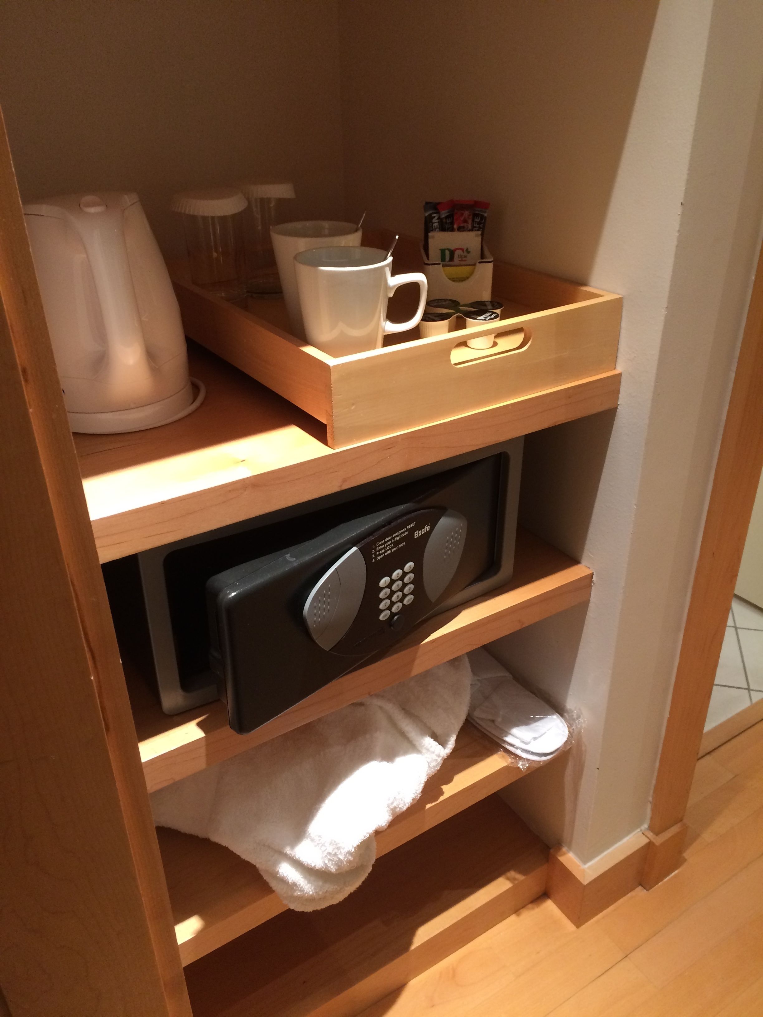 A wooden shelf with a microwave, a white mug, and a coffee maker.