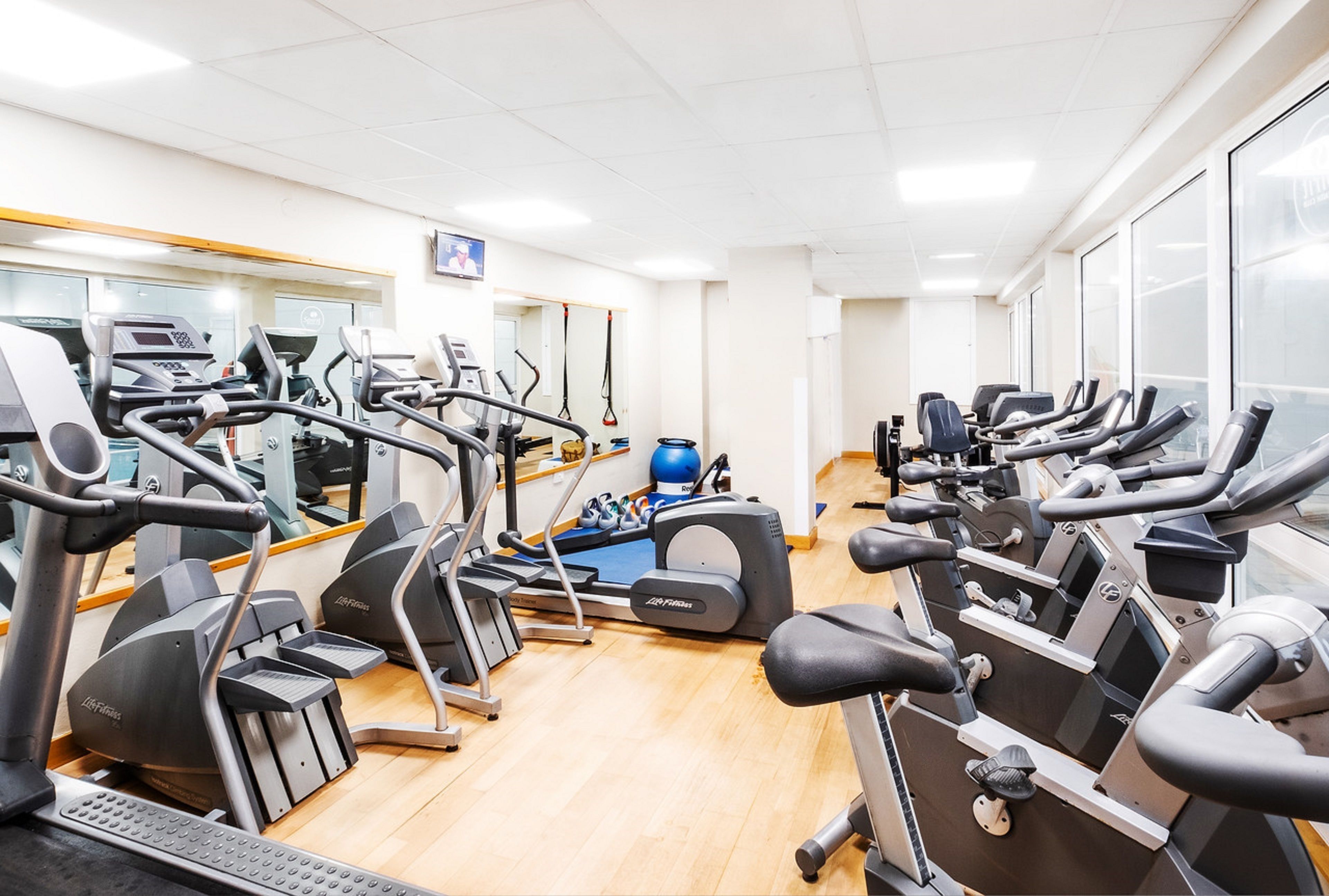 A gym with multiple treadmills, ellipticals, and a rowing machine.