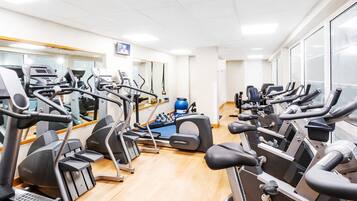 A gym with multiple treadmills, ellipticals, and a rowing machine.