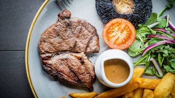 A plate with grilled steak, a grilled mushroom, a tomato slice, a salad, and French fries.