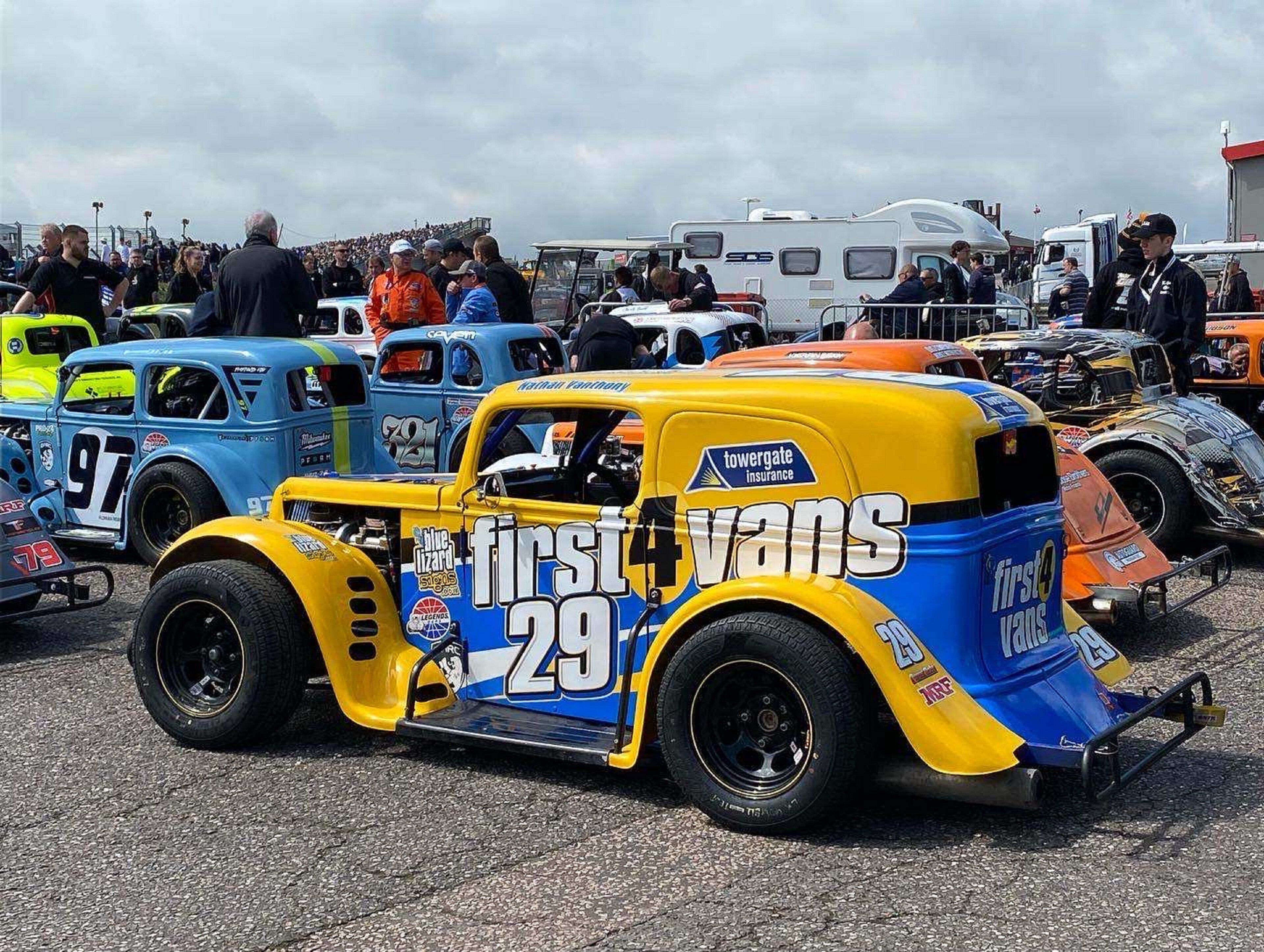 A vintage race car with the number 29 parked among other vehicles at a car show.