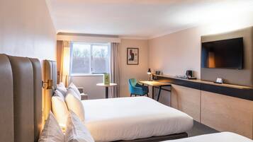 Habitación de hotel con dos camas, un escritorio, una silla, un televisor y una ventana con cortinas.