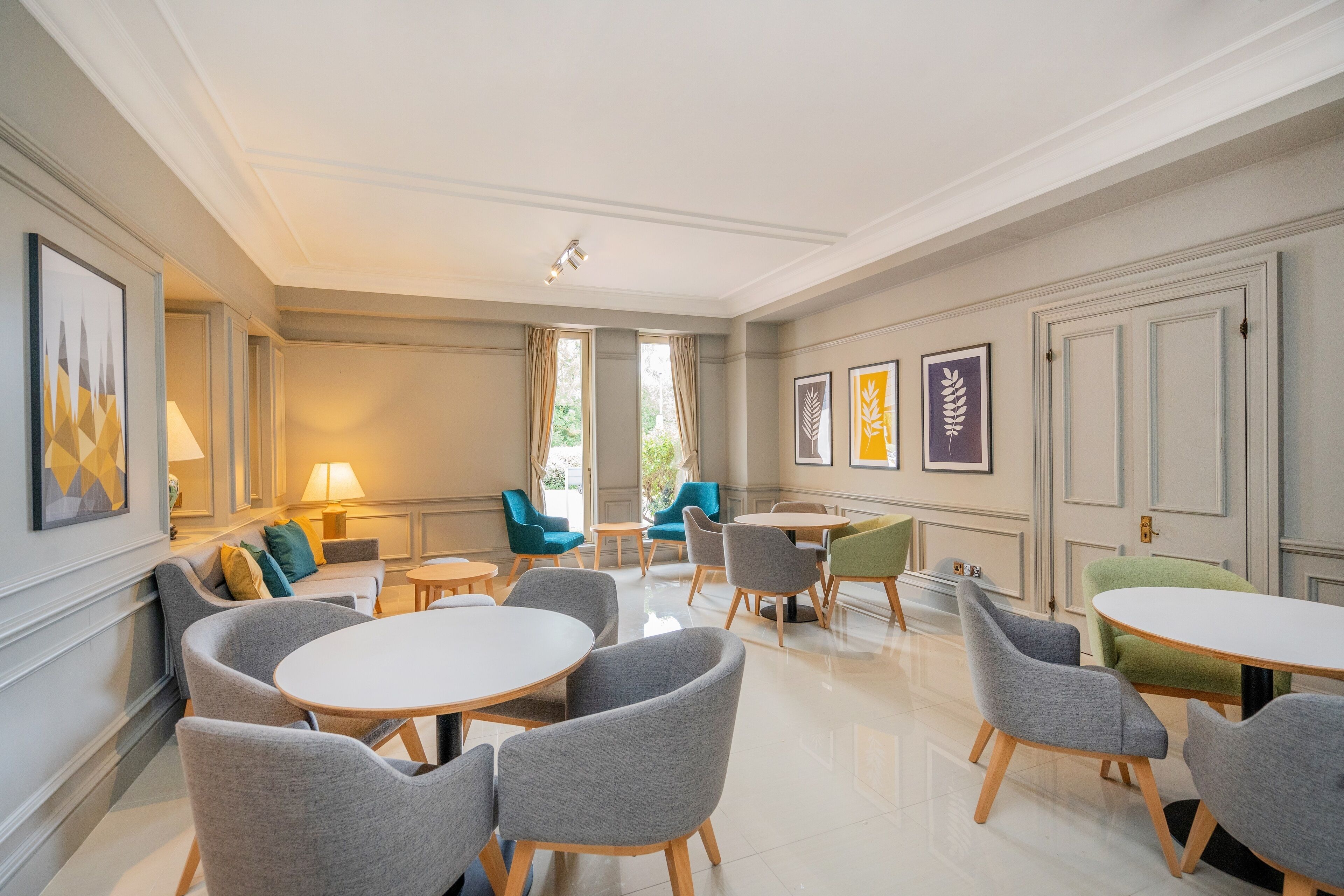 A modern hotel room with a dining area, multiple seating options, and artwork on the walls.