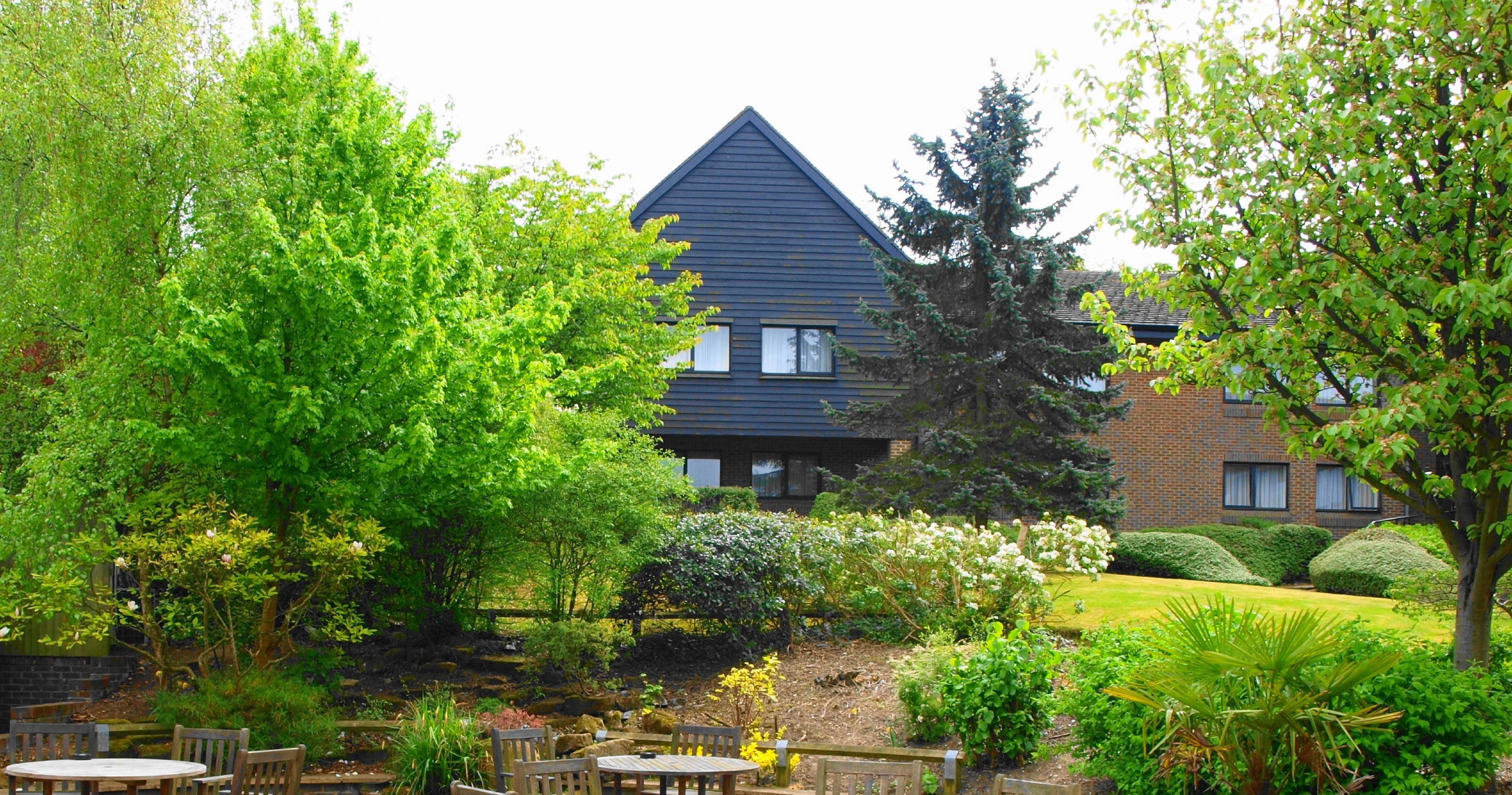 A residential building with a dark blue exterior, surrounded by lush greenery and a well-maintained garden.