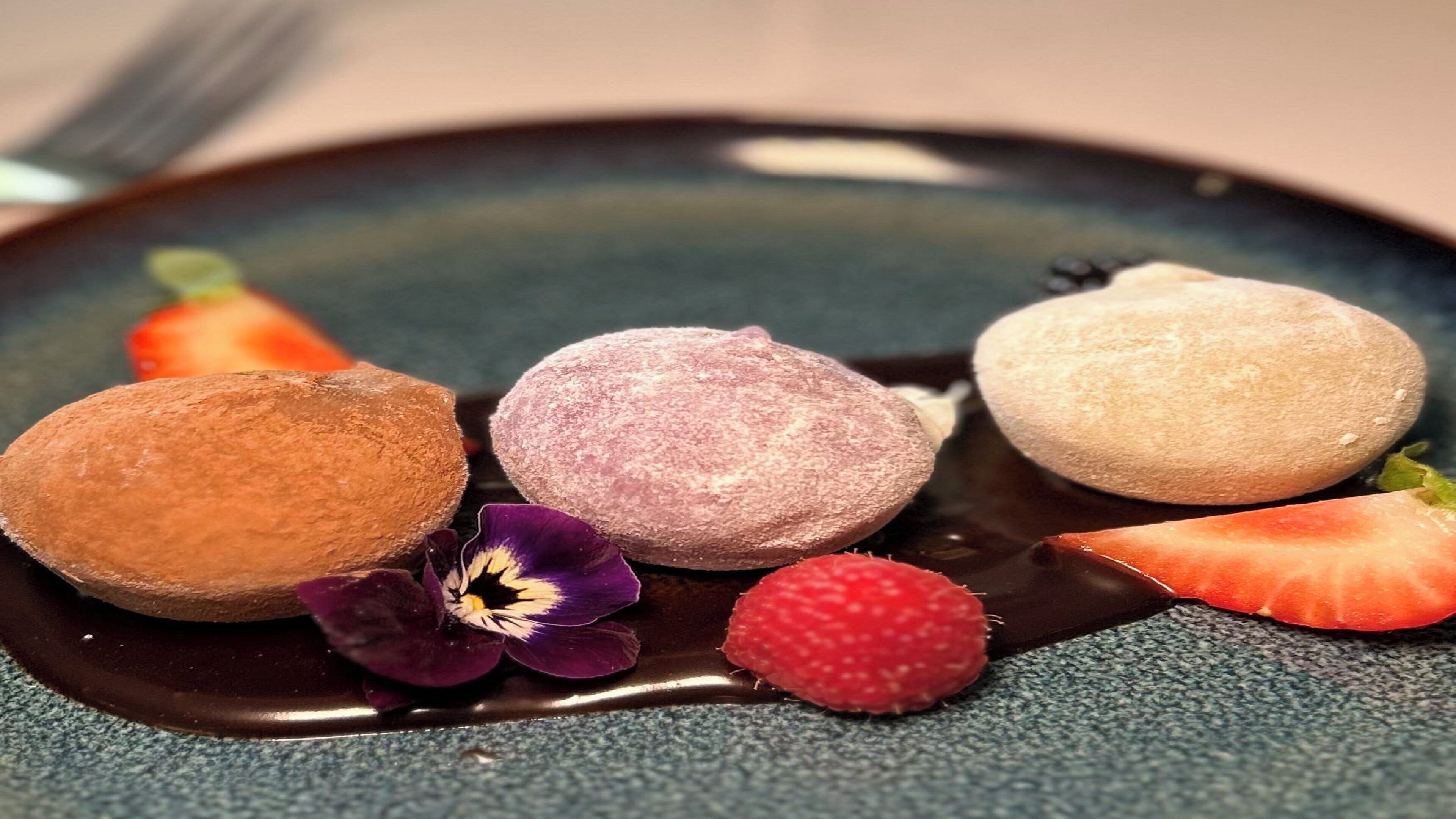 A dessert plate with three round pastries and some fruit.
