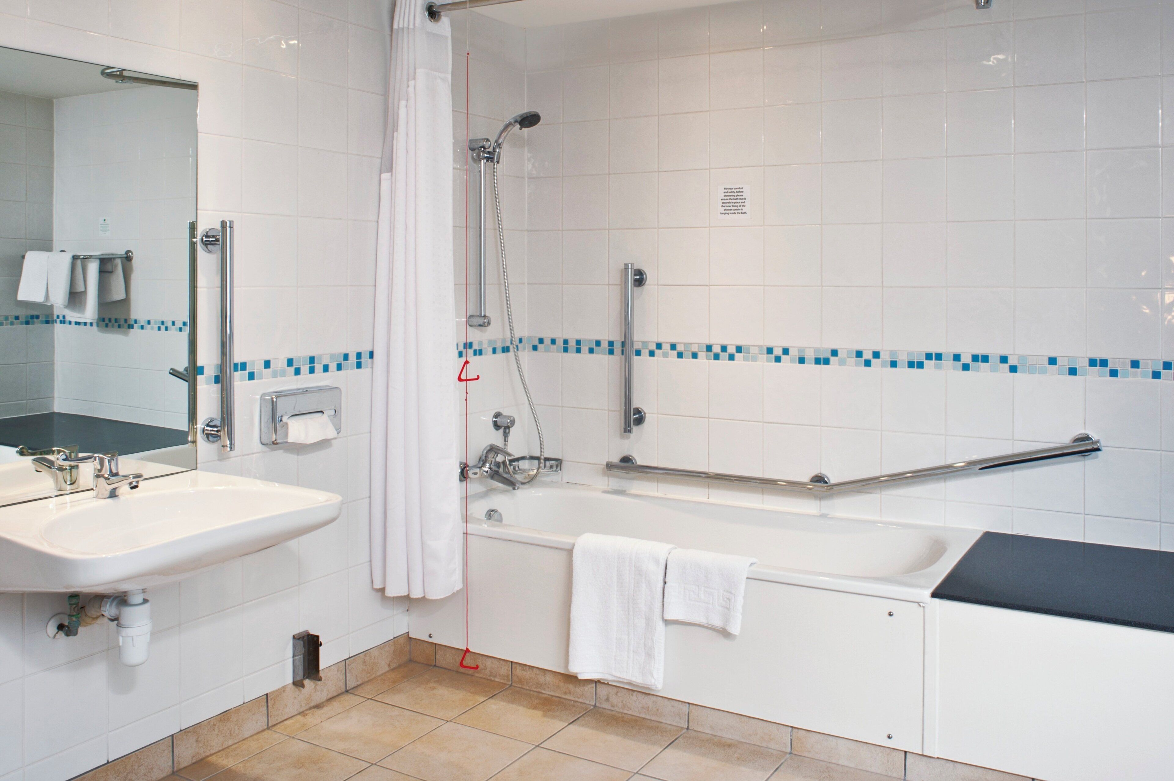 Een badkamer met een wastafel, spiegel, douche en bad.