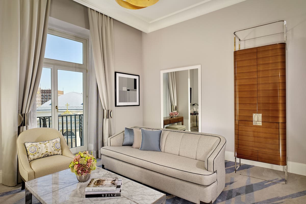 A modern living room with a sofa, armchair, and a coffee table with a vase of flowers.